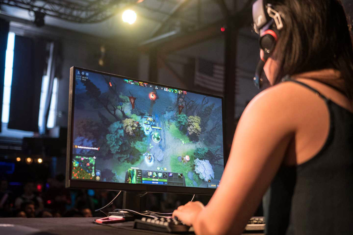 Person with headphones on, focused on playing Dota on a screen in front of them