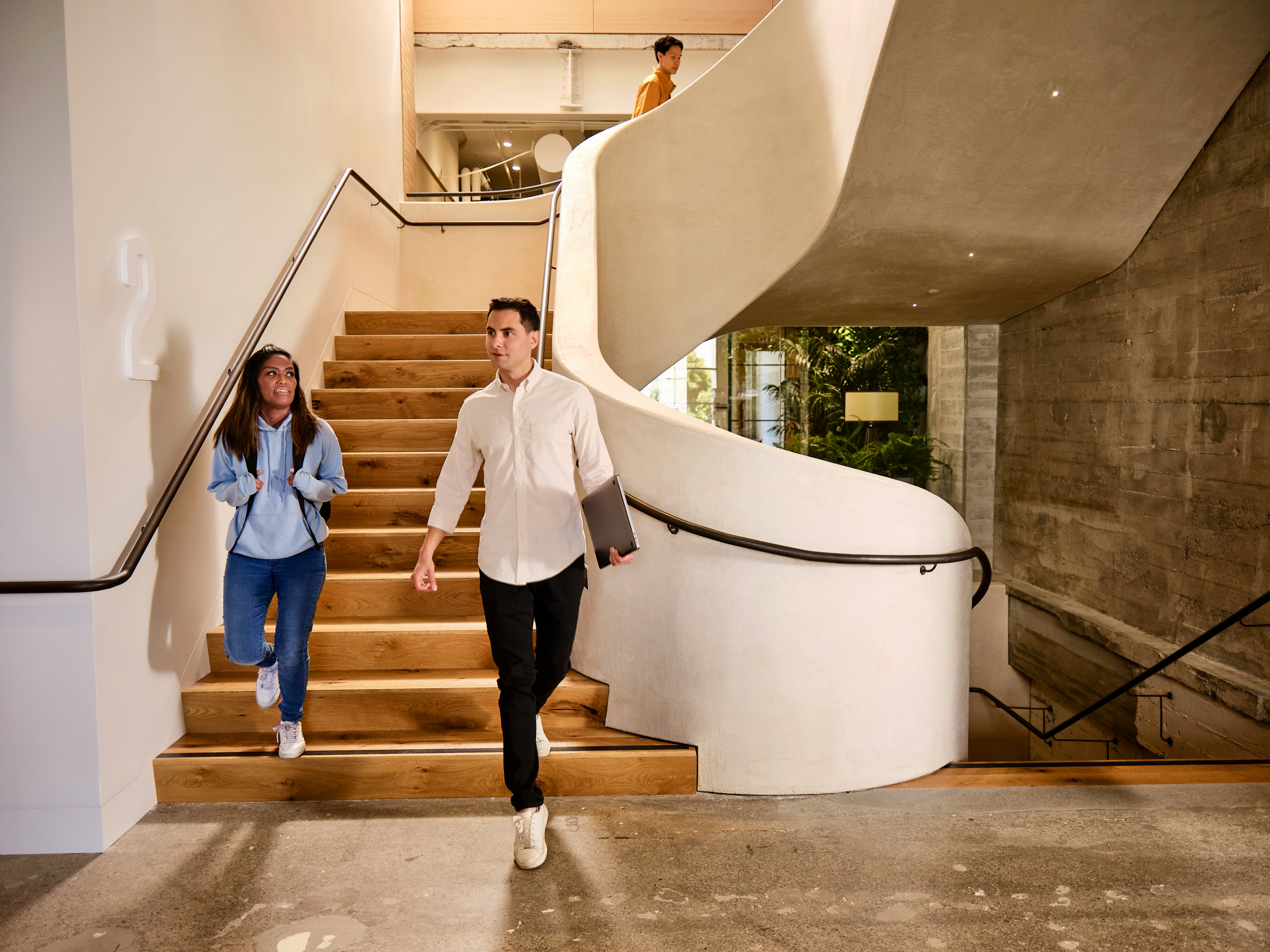 Two people reaching the bottom of a flight of stairs while talking